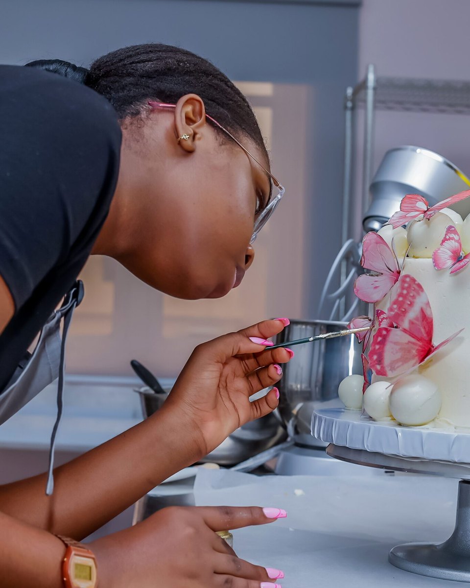 Piping sugar butterflies onto a pink cake